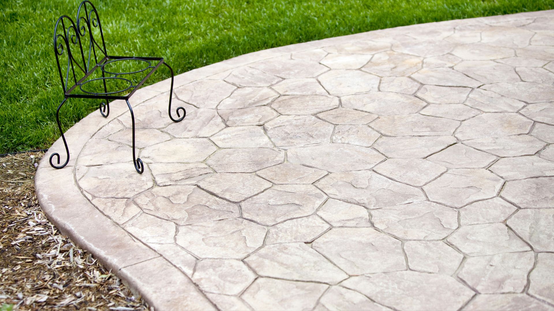 A wrought iron chair sitting on top of a stone patio