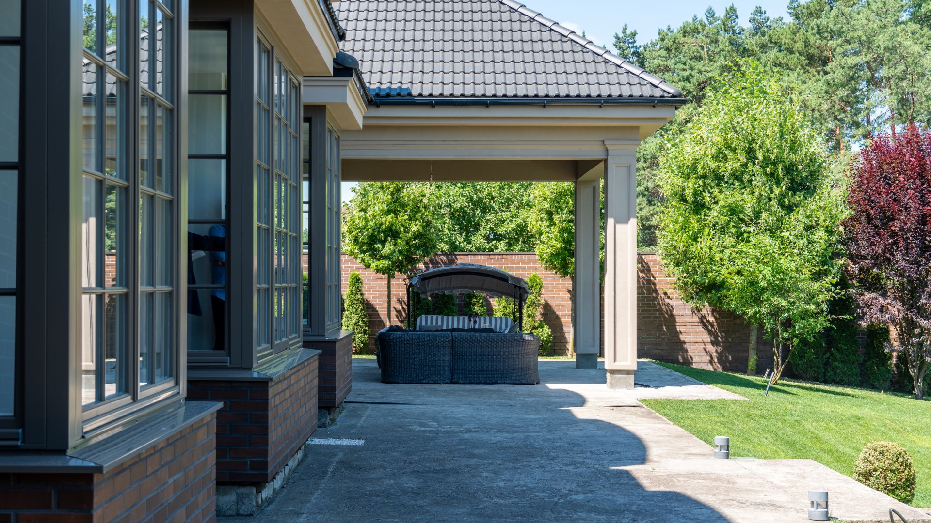 A walkway leading to a covered patio with a grill